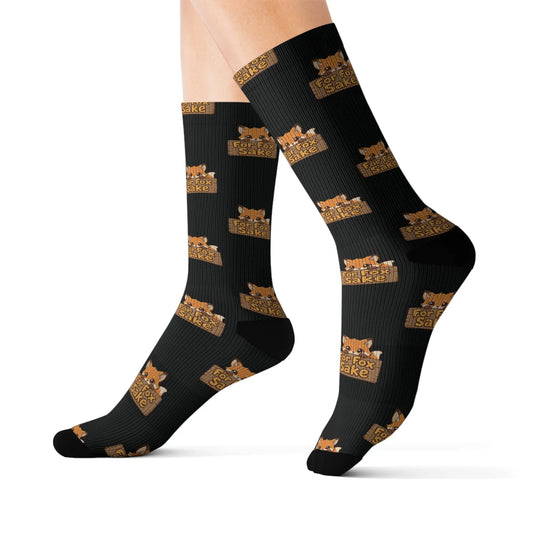 Black socks with gold fox and text pattern worn by a person on a white background